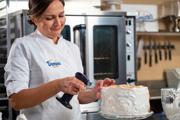 A woman with a blowtorch finishing a cake